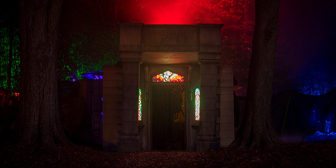 The author's Halloween haunt at night: fog and dim ochre light around a doorway draped in black fabric.